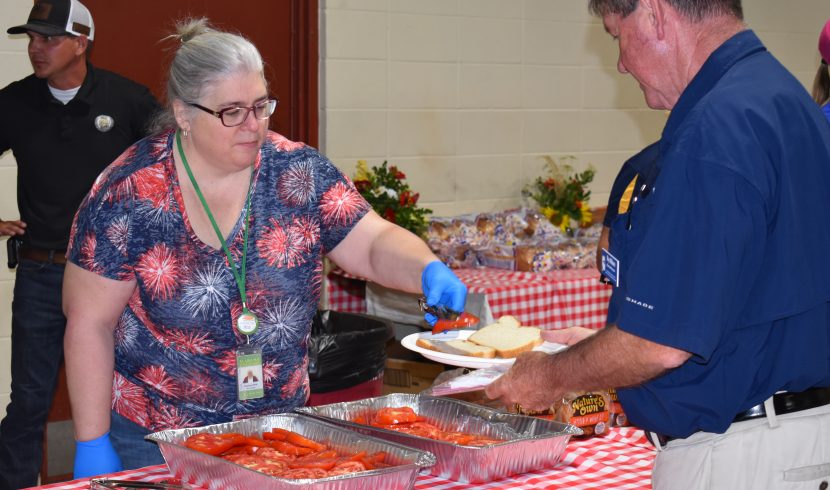 A woman puts a slice of tomato on a man's plate