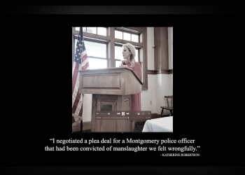 This is a screenshot from the ad of Robertson speaking at a podium.